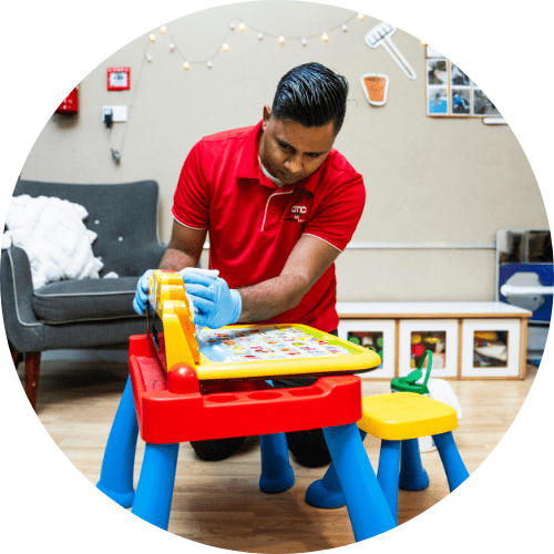 AMC Commercial Cleaning cleaner in uniform at childcare facility sanitising toys, little desks, chairs